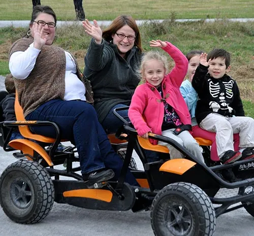 Family waving from a pedal cart