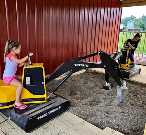 Two young girls using toy backhoes at Ellms Farm