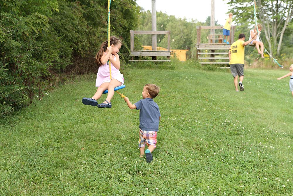 young boy helping girl back up on zipline